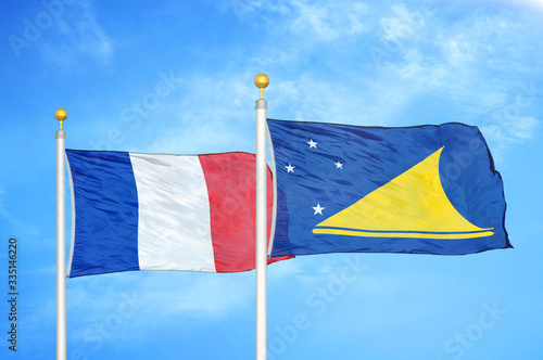 France and Tokelau two flags on flagpoles and blue cloudy sky photo