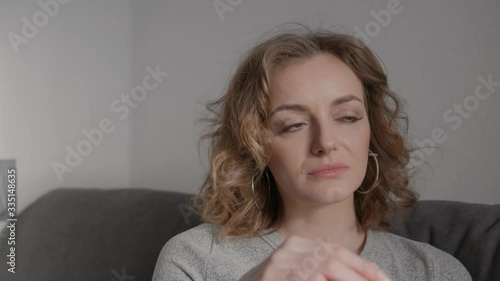 Close up shot of shy happy blonde blonde woman enjoying eating a big banana sitting on sofa white wall background smiling looking into camera