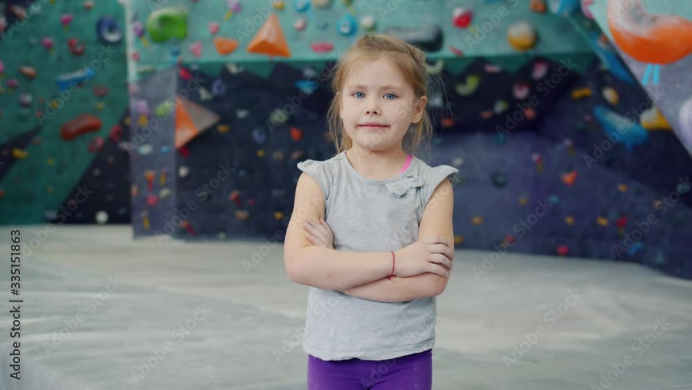 Portrait of beautiful little girl in indoor climbing facility standing alone with arms crossed looking at camera. Happy childhood and leisure activities concept. Portrait of beautiful little girl in indoor climbing facility standing alone with arms crossed looking at camera. Happy childhood and leisure activities concept.