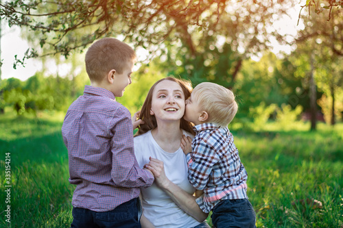 Mom with two sons in the Park. Child is kissing his mother. Happy motherhood