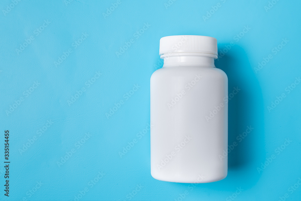 White medicine plastic package for pills. Bottle mockup on a blue background. Copy space White medicine plastic package for pills. Bottle mockup on a blue background. Copy space