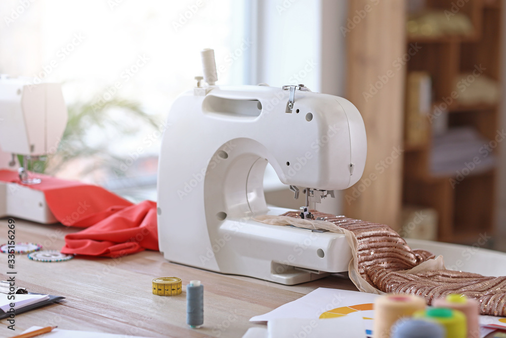 Modern sewing machine on table in tailor's workshop