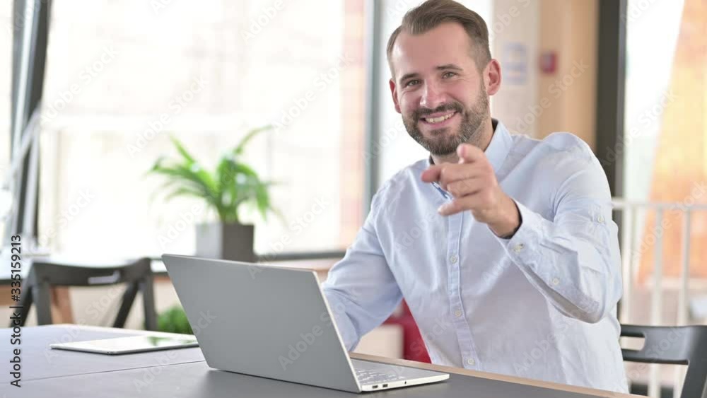 Cheerful Young Man with Laptop Pointing with Finger Cheerful Young Man with Laptop Pointing with Finger