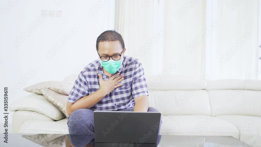 Young man having cough during work at home with laptop and wearing a mask to prevent coronavirus. Shot in 4k resolution Young man having cough during work at home with laptop and wearing a mask to prevent coronavirus. Shot in 4k resolution