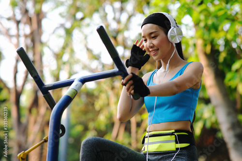 young woman doing exercise in the park and listening music