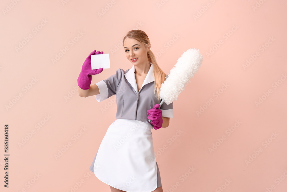 Beautiful young chambermaid with business card on color background Beautiful young chambermaid with business card on color background