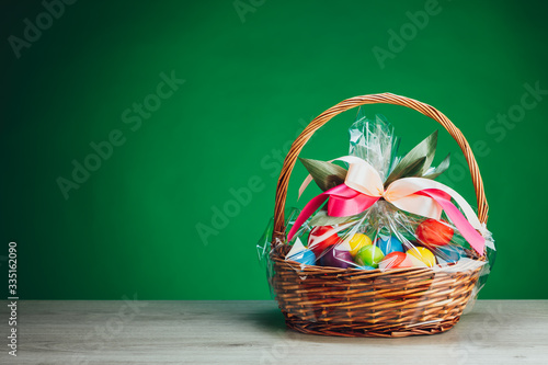 Easter gift basket with multicolor eggs, green background photo