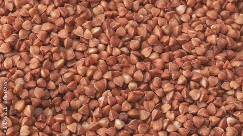 Pile of uncooked brown buckwheat, close shot. Dolly shot of texture of buckwheat grains. Close up view on buckwheat grains, abstract background Pile of uncooked brown buckwheat, close shot. Dolly shot of texture of buckwheat grains. Close up view on buckwheat grains, abstract background