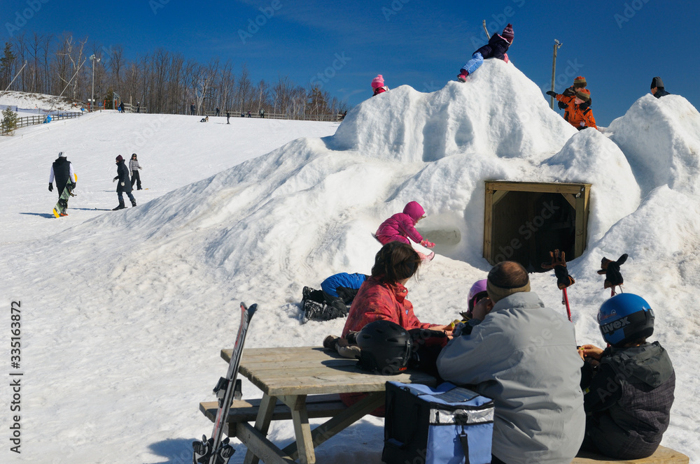 Family picnic in the snow with children on a snow pile at Lakeridge ski resort Ontario