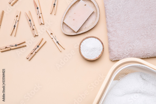 Soap, clothes pegs, towel and laundry detergent on color background
