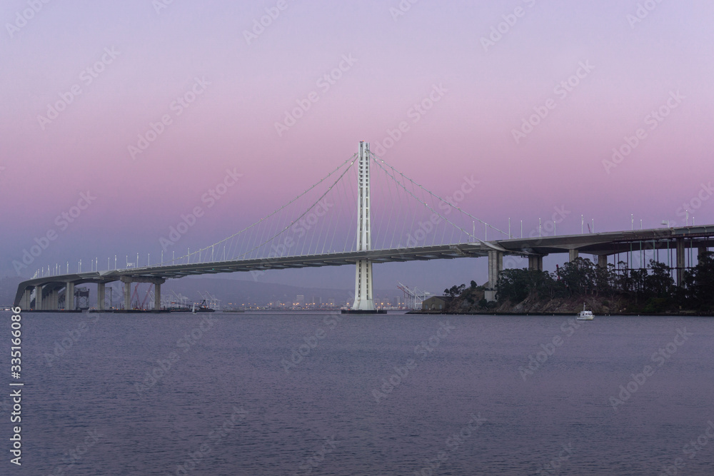 Fototapeta premium Bay Bridge from Treasure Island with natural purple haze sunset. Port of Oakland in the background.