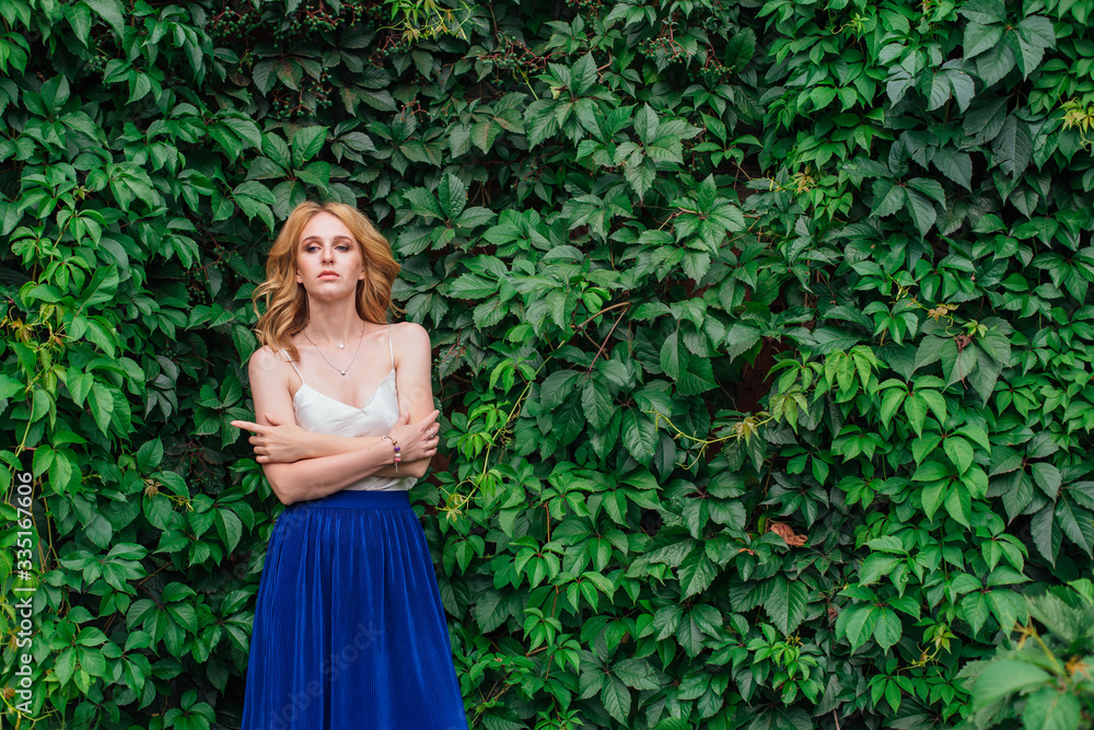 Portrait of a young beautiful woman, standing next to the wall of wild grape leaves. Portrait of a young beautiful woman, standing next to the wall of wild grape leaves.