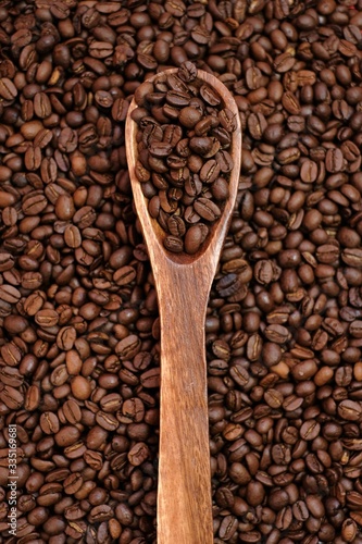 Coffee beans in a wooden spoon on coffee beans background.Roasted coffee beans close-up.