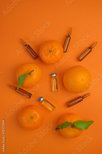 Vitamin C concept. Tangerines fruits, vitamin C in glass ampoules on a bright orange background.ampoules and Serum with Vitamin C. Organic cosmetics concept. Medicine and health concept. 