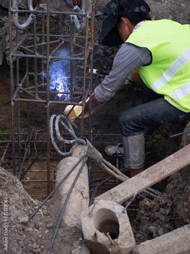 Worker in protective mask welding steel railings outdoors