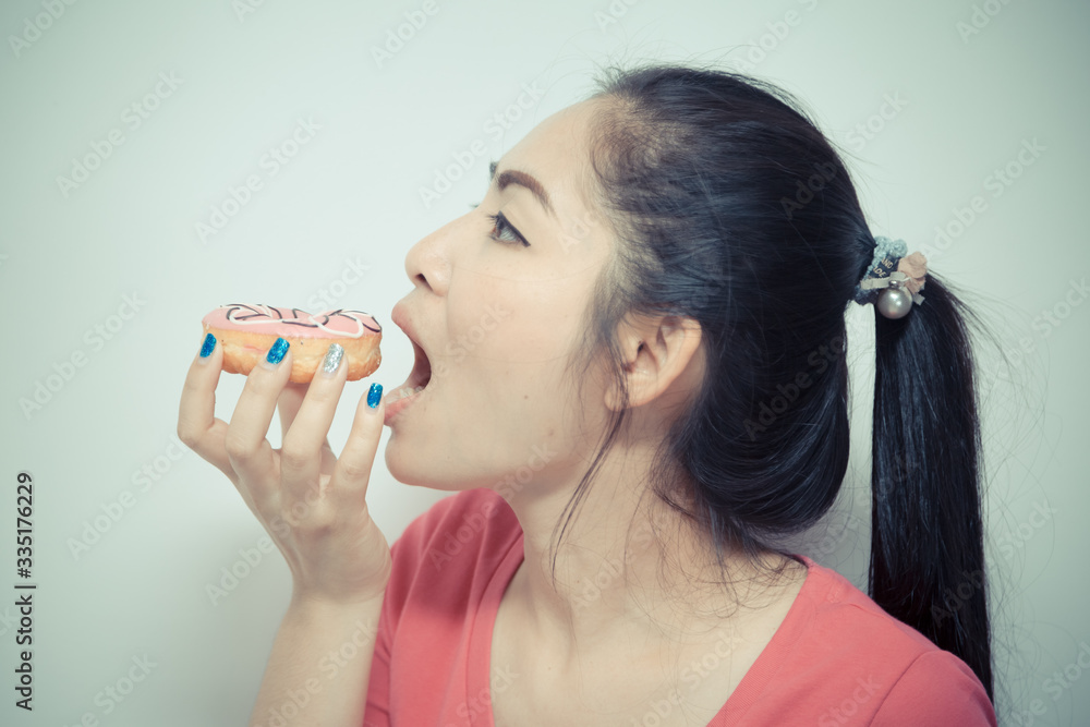 Beautiful woman long black hair eating pink donut isolated on white Beautiful woman long black hair eating pink donut isolated on white