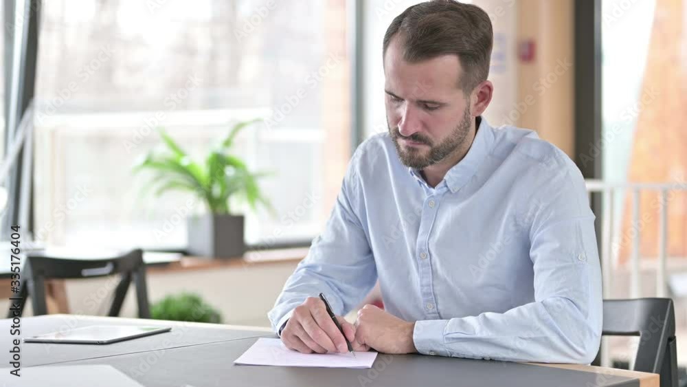 Focused Young Man doing Paperwork in Office Focused Young Man doing Paperwork in Office
