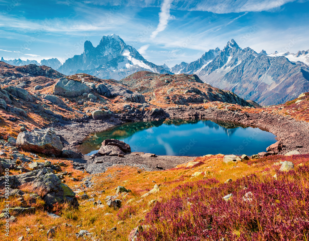 Red blueberry leaves cover the mountain slopes. Sunny autumn view of Cheserys lake (Lac De Cheserys), Chamonix location. Nice morning scene of Vallon de Berard Nature Preserve, Graian Alps, France.