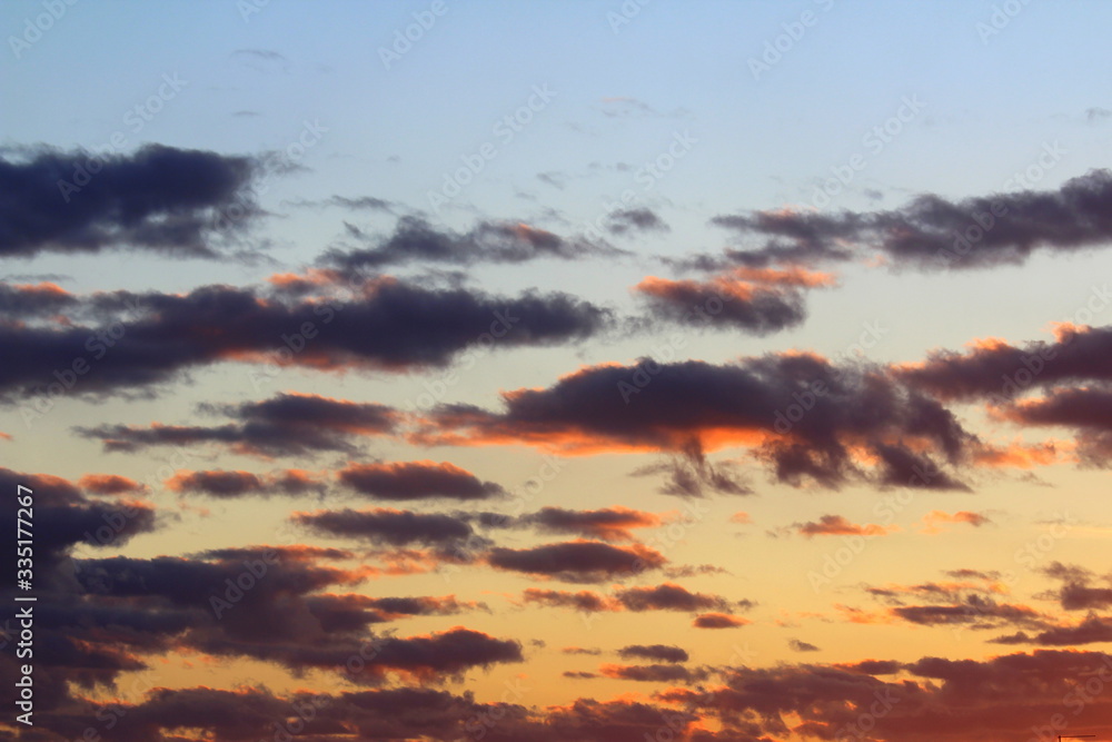 Clouds in the blue sky at sunset or dawn backlit by the sun. Place for text and design. Clouds in the blue sky at sunset or dawn backlit by the sun. Place for text and design.