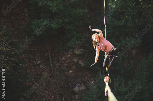 Fotografía A woman is walking along a stretched sling over a forest.