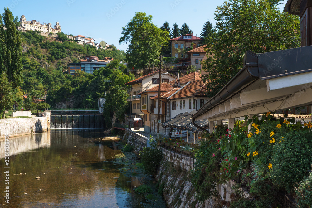 The view of the river Milavitsa, houses and flowers on the shore in the summer in Sarajevo, Bosnia and Herzegovina