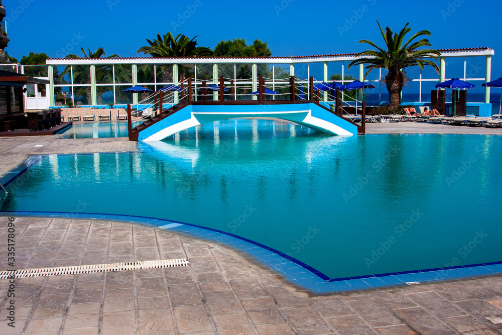 Beautiful blue pool, bridge over it and blue sky