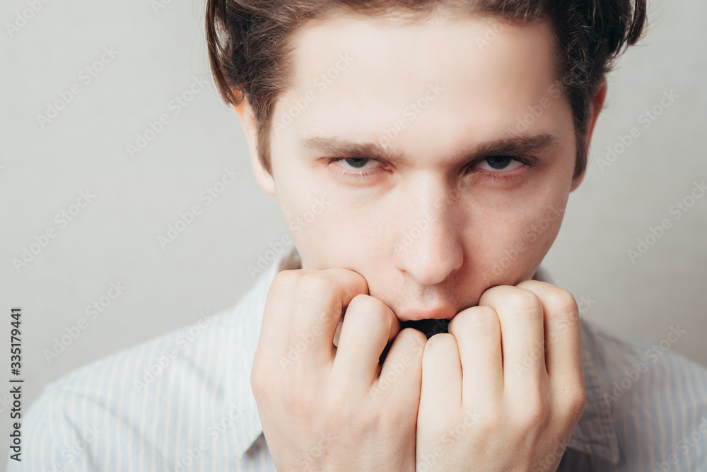 Closeup portrait of a young handsome man biting his finger nails with a craving for something or anxious. Negative human emotion facial expression feeling Closeup portrait of a young handsome man biting his finger nails with a craving for something or anxious. Negative human emotion facial expression feeling