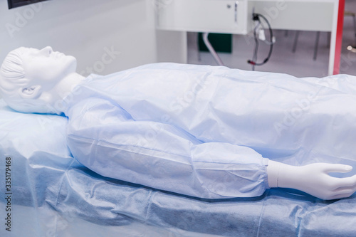 A mannequin in medical clothes lies on a table