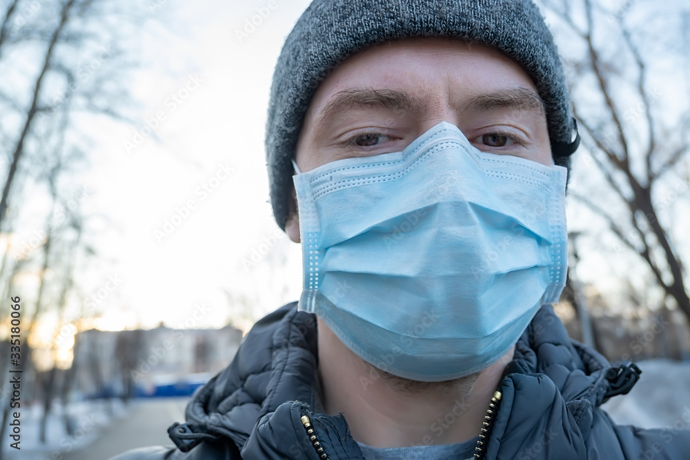 selfie of a man in an anti virus medical breathing mask against the background of an alley of a city street in winter selfie of a man in an anti virus medical breathing mask against the background of an alley of a city street in winter
