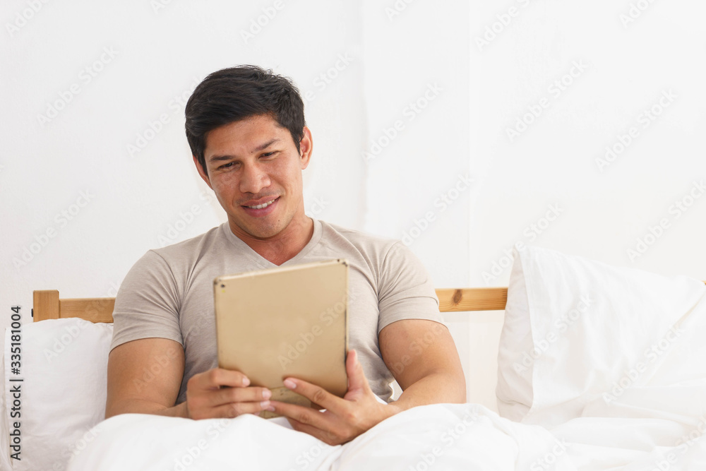 Young handsome Asian man is catching up on news with his tablet. Young handsome Asian man is catching up on news with his tablet.