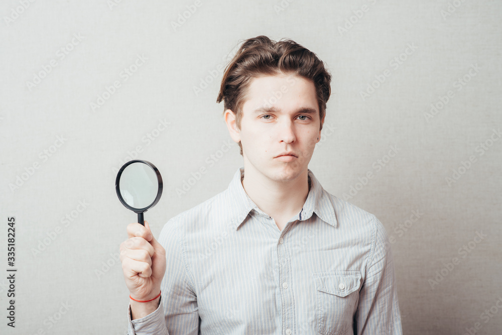 young man looking through a magnifying glass young man looking through a magnifying glass