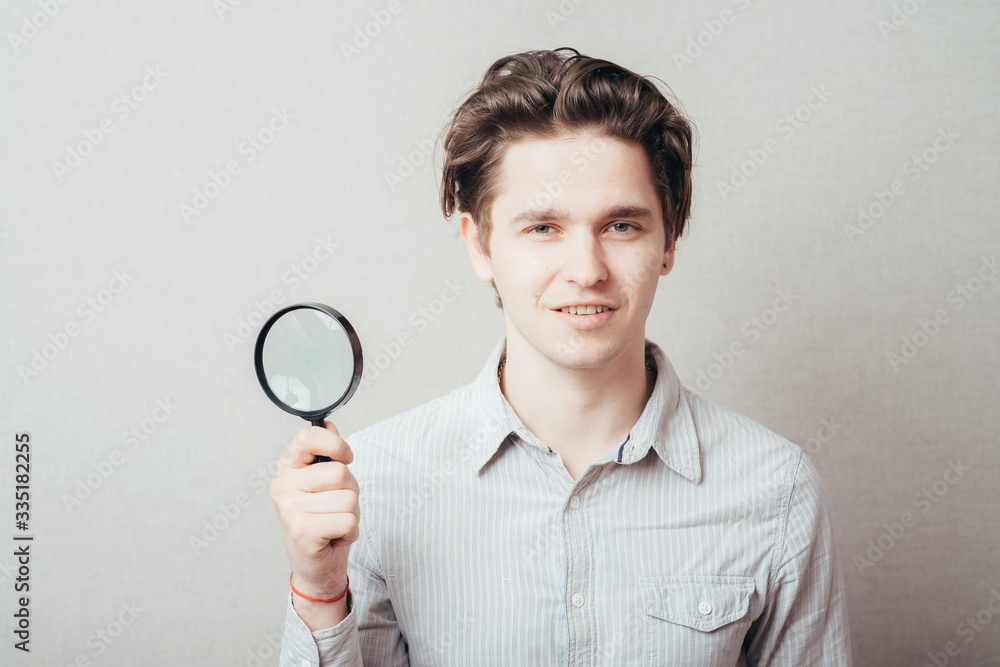 young man looking through a magnifying glass young man looking through a magnifying glass