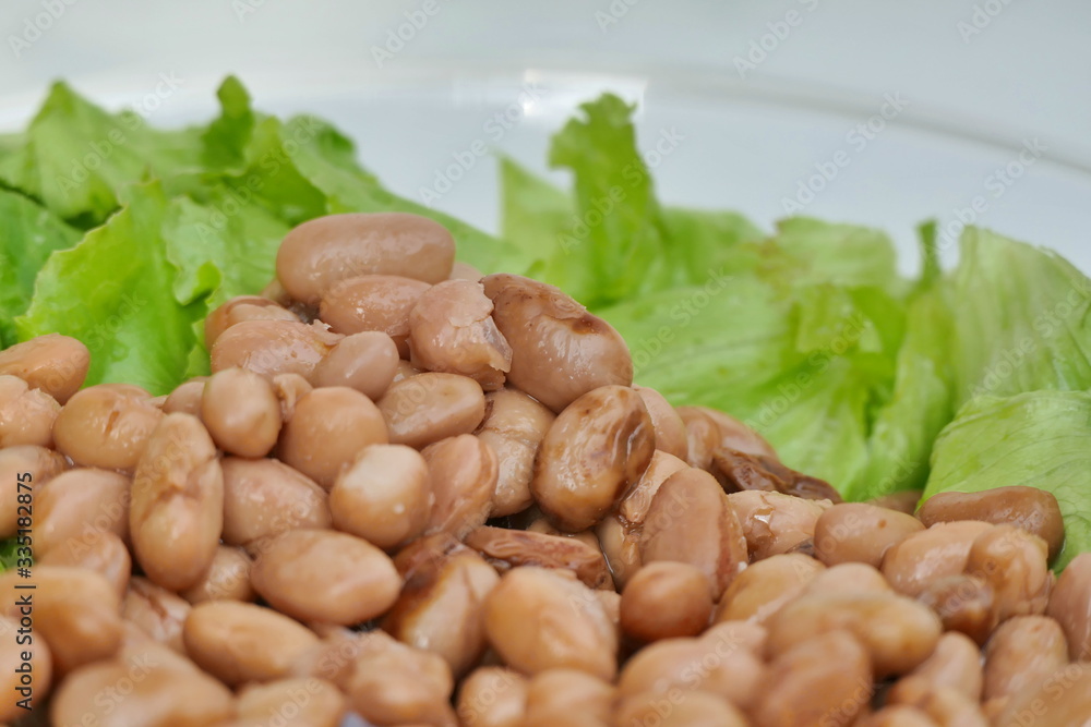 Fototapeta premium Beans and green lettuce on dish - closeup view
