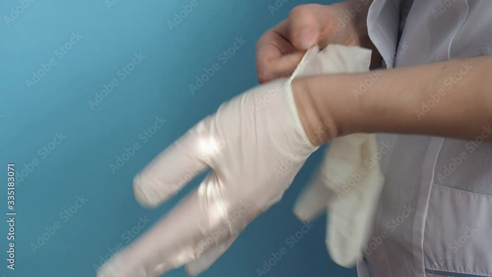 A doctor in a white coat puts medical latex gloves on his hands A doctor in a white coat puts medical latex gloves on his hands
