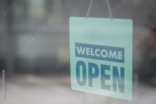 Open and welcome sign broad through the glass of window