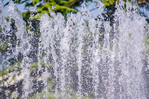 Splashes of water against the green background. Water sprays in sunny day close-up.
