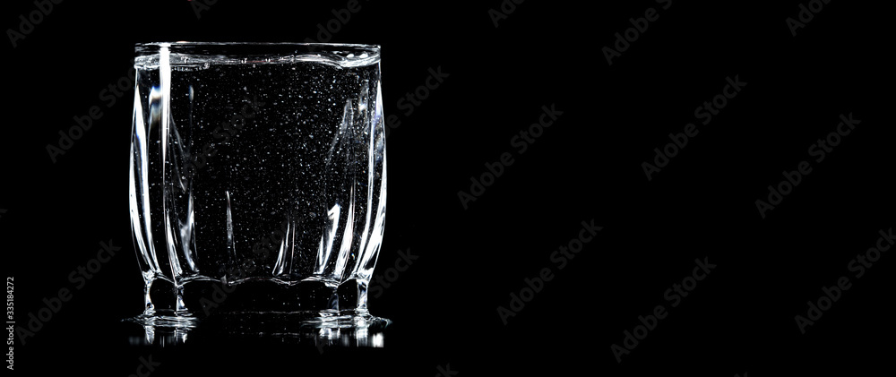 A glass of water is isolated on a black .