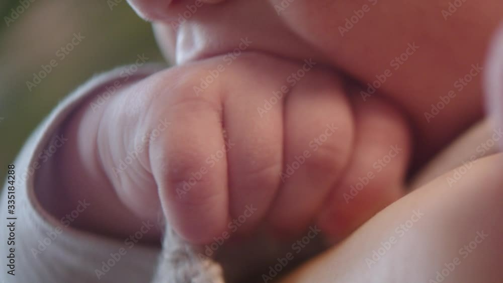 Cute newborn baby chewing on his fist. Close up selective focus Cute newborn baby chewing on his fist. Close up selective focus