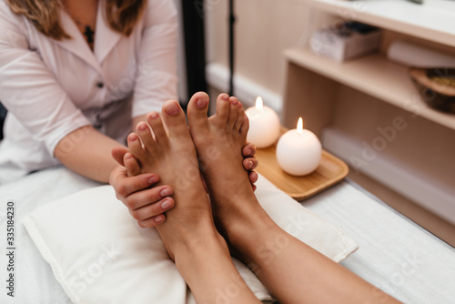 Woman having reflexology foot massage in wellness spa center