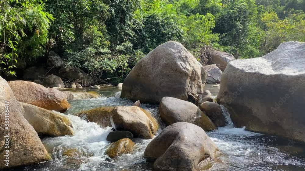 A mountain stream flows through large stones, foam from the flow of water.jungle A mountain stream flows through large stones, foam from the flow of water.jungle