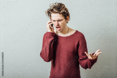 The man speaks on the phone cursing. On a gray background. photo