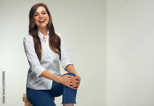 Happy woman in white shirt sitting on chair.