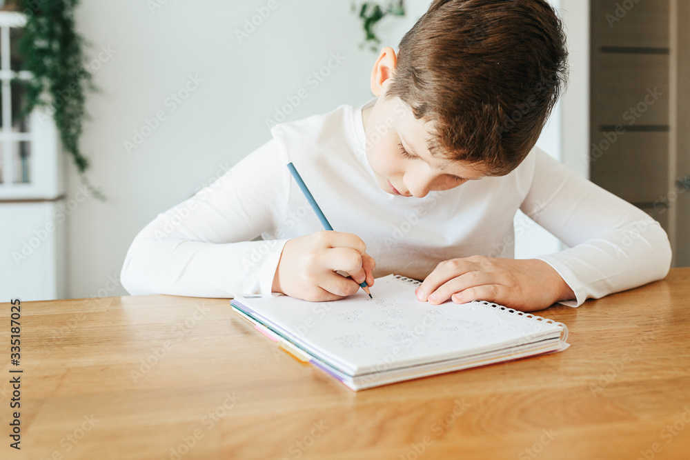 Healthy child writing with pen, staying at home. Homeschooling concept Healthy child writing with pen, staying at home. Homeschooling concept