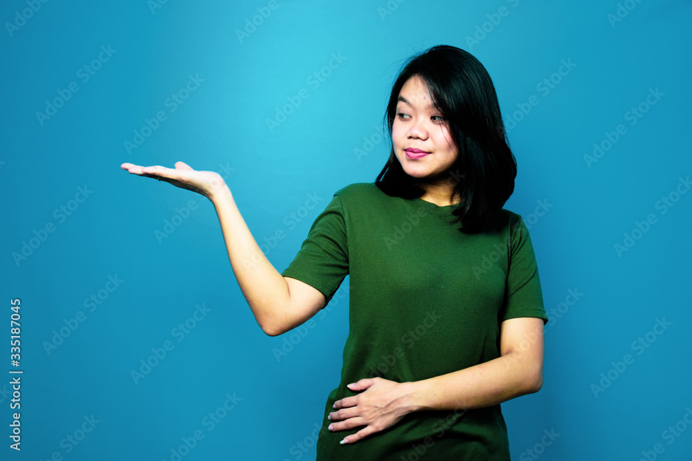 Portrait of Young beautiful asian women using Green T-shirt with blue isolated background, copyspace on the palm Portrait of Young beautiful asian women using Green T-shirt with blue isolated background, copyspace on the palm
