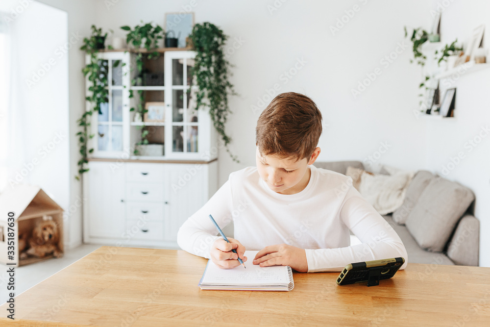 Healthy child writing with pen, staying at home. Homeschooling concept Healthy child writing with pen, staying at home. Homeschooling concept