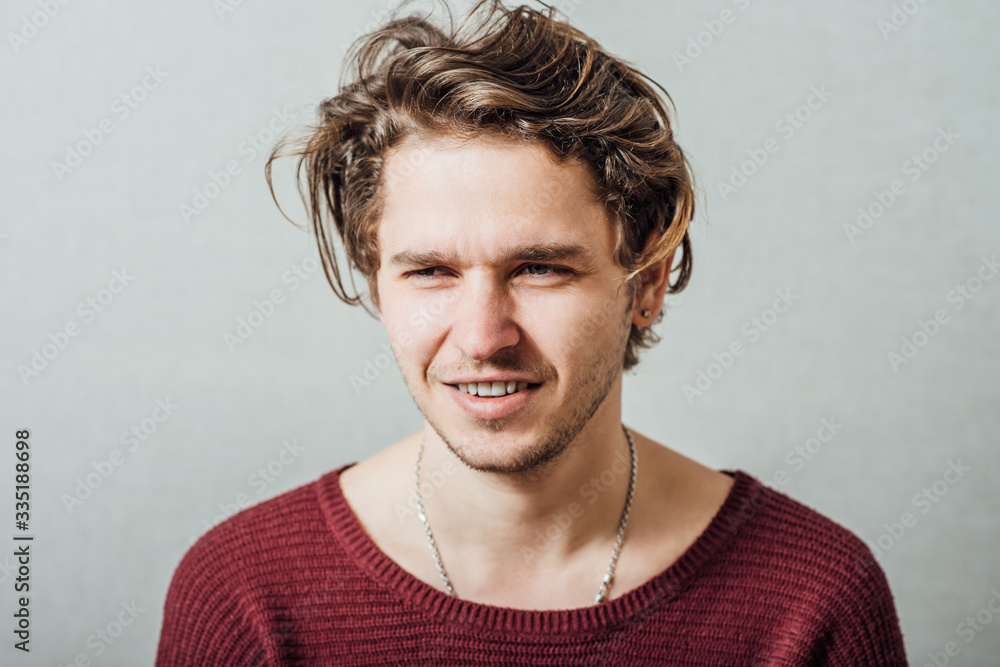 Fototapeta premium Closeup portrait of a happy young man smiling on gray background