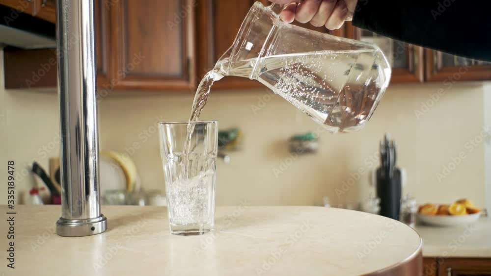 water is poured from a decanter into a glass in the kitchen water is poured from a decanter into a glass in the kitchen