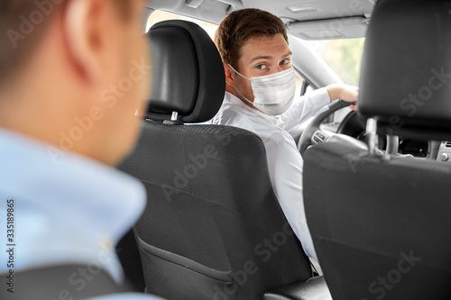 health protection, safety and pandemic concept - male taxi driver wearing face protective medical mask driving car with passenger © Syda Productions