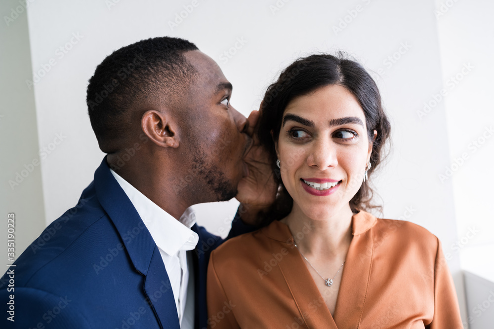 Businessman Whispering Into Female Partner's Ear Businessman Whispering Into Female Partner's Ear