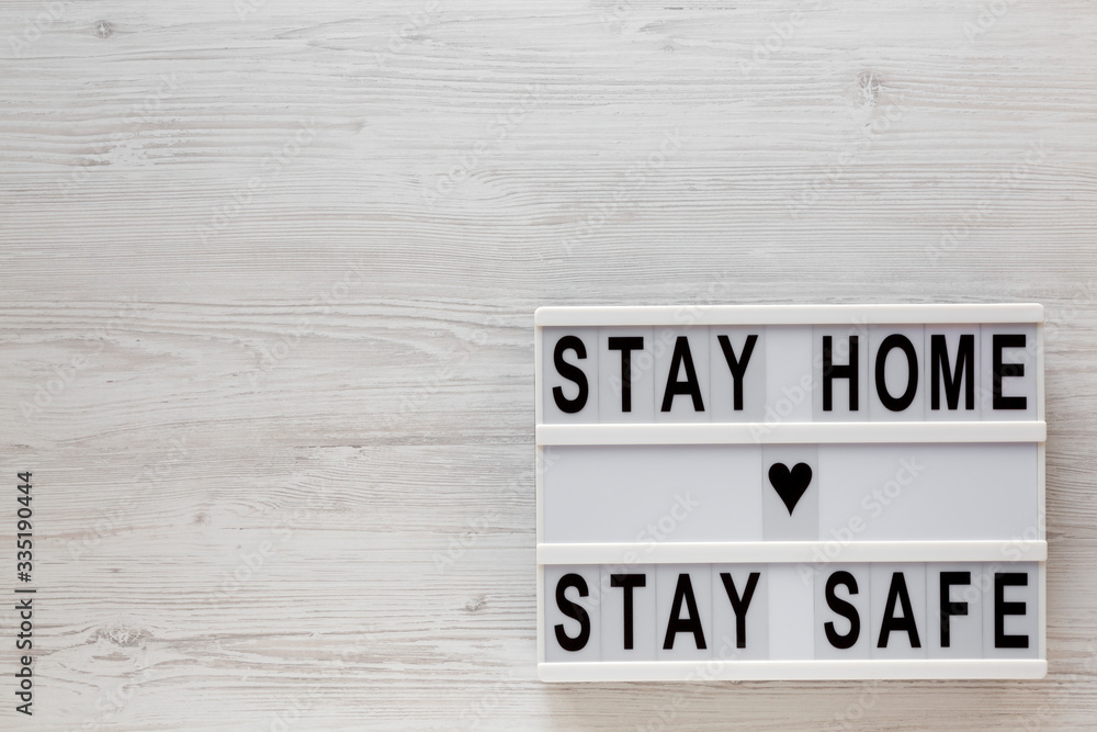 'Stay home stay safe' words on a lightbox on a white wooden surface, top view. Overhead, from above, flat lay. Space for text. 'Stay home stay safe' words on a lightbox on a white wooden surface, top view. Overhead, from above, flat lay. Space for text.